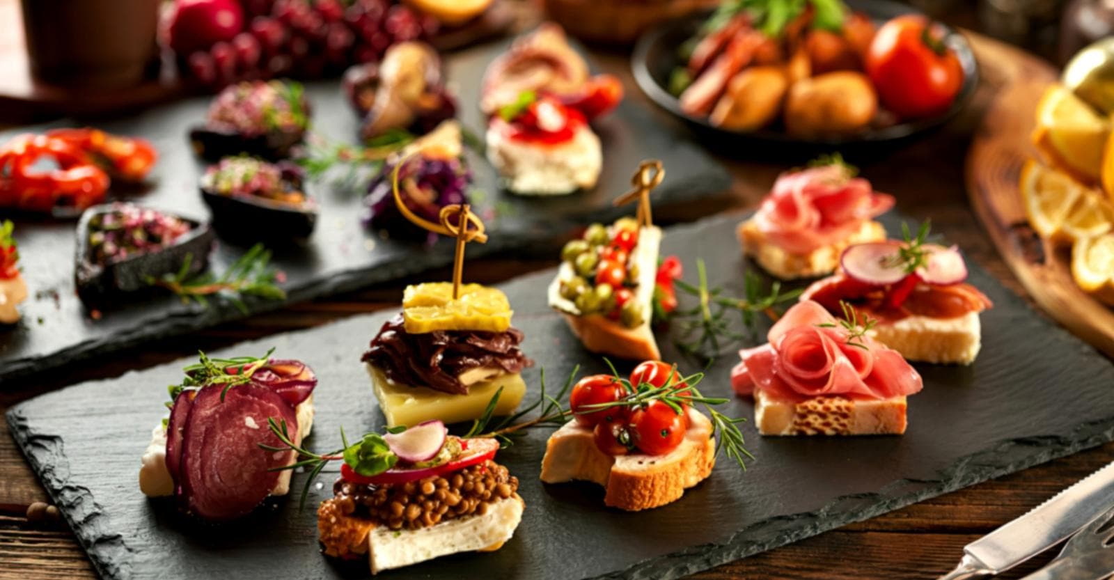 Verschiedene Tapas auf Schieferplatten, bunt garniert mit Kräutern und Gemüse.