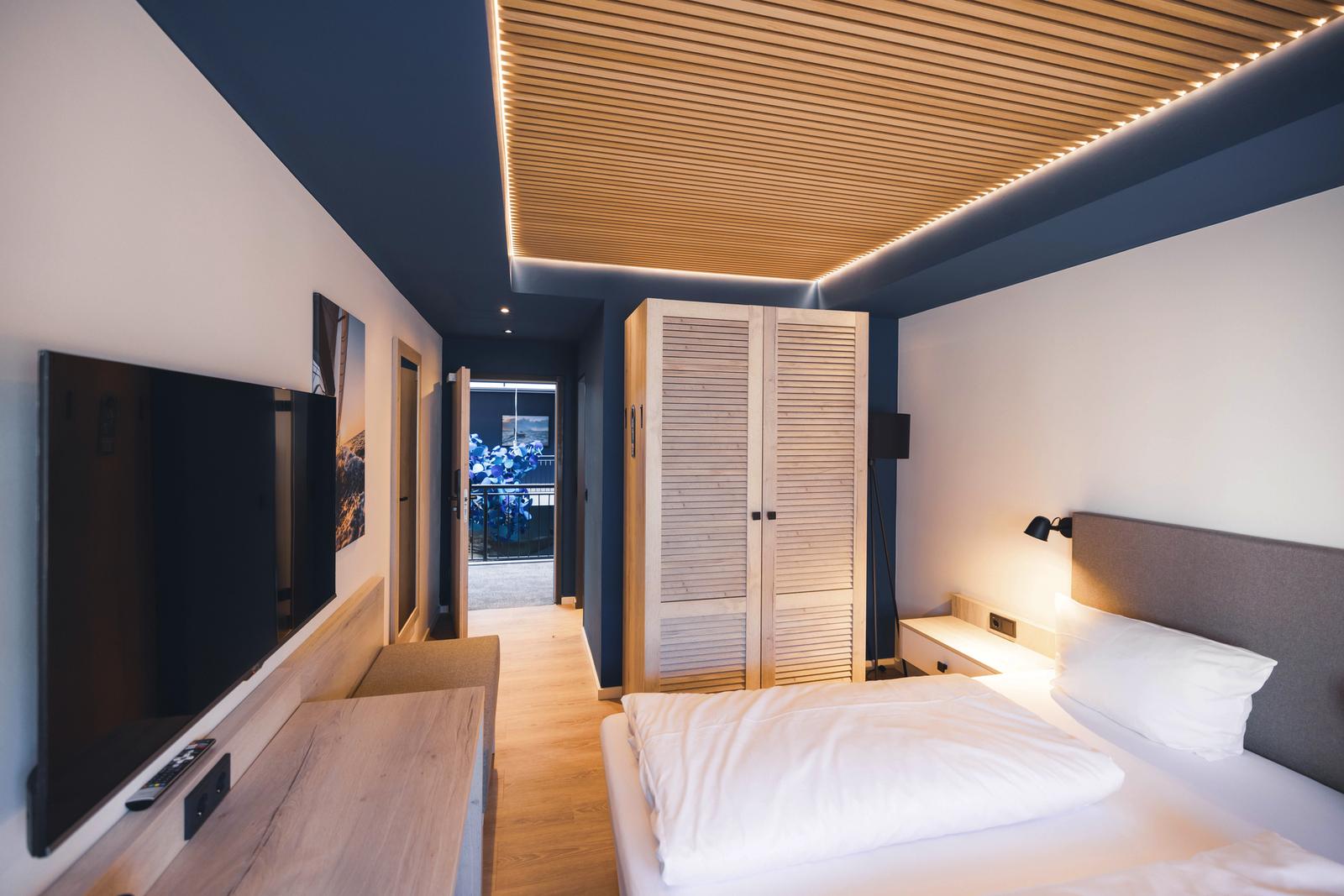 Modernes Hotelzimmer mit eleganten Holzelementen und Balkonblick im THE OCEANs Hotel .