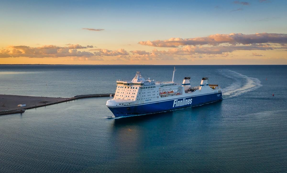 Ein Schiff verlässt den Hafen, segelt in die offene Ostsee bei Sonnenuntergang.