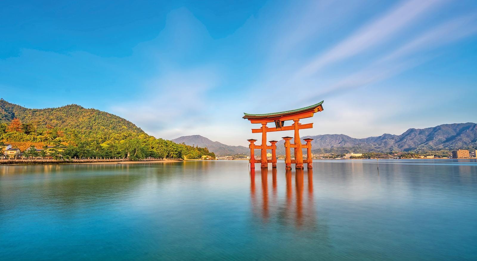 Schöne Szenerie in Japan mit schwimmendem Torii-Tor vor ruhiger Küste und Bergen.