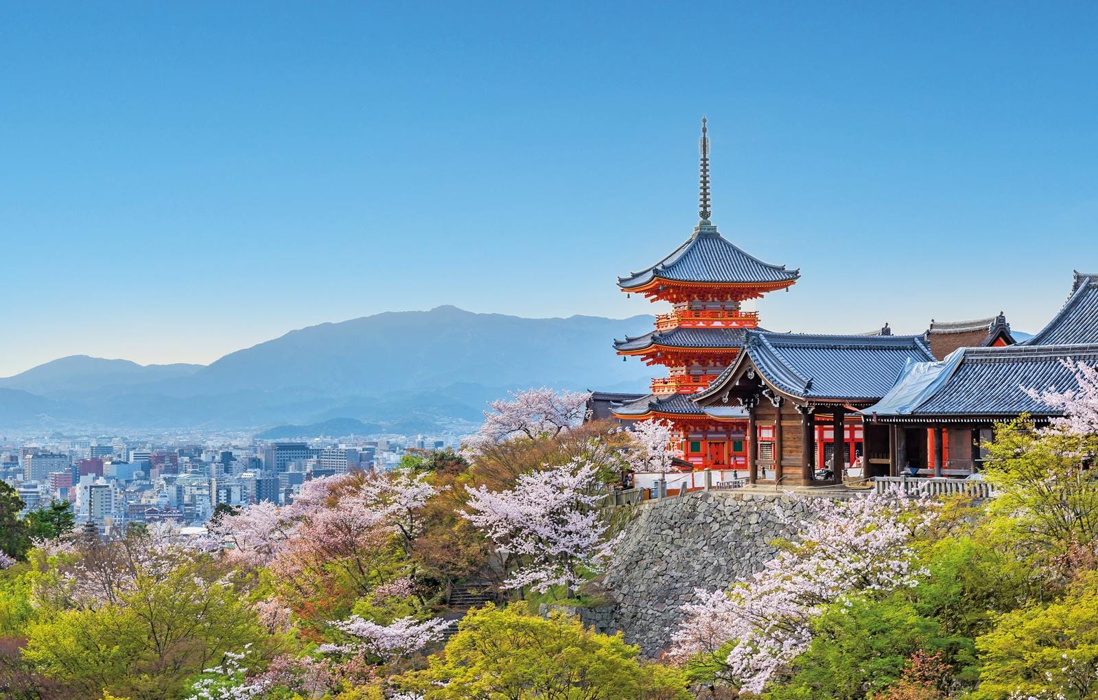 Traditioneller Tempel in Kyoto, Japan, umgeben von Kirschblüten und Blick auf die Stadt.