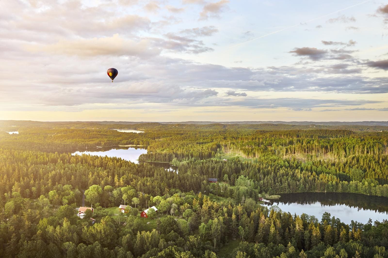 Landschaft mit Wäldern und Seen, Heißluftballon am Himmel, Schweden.