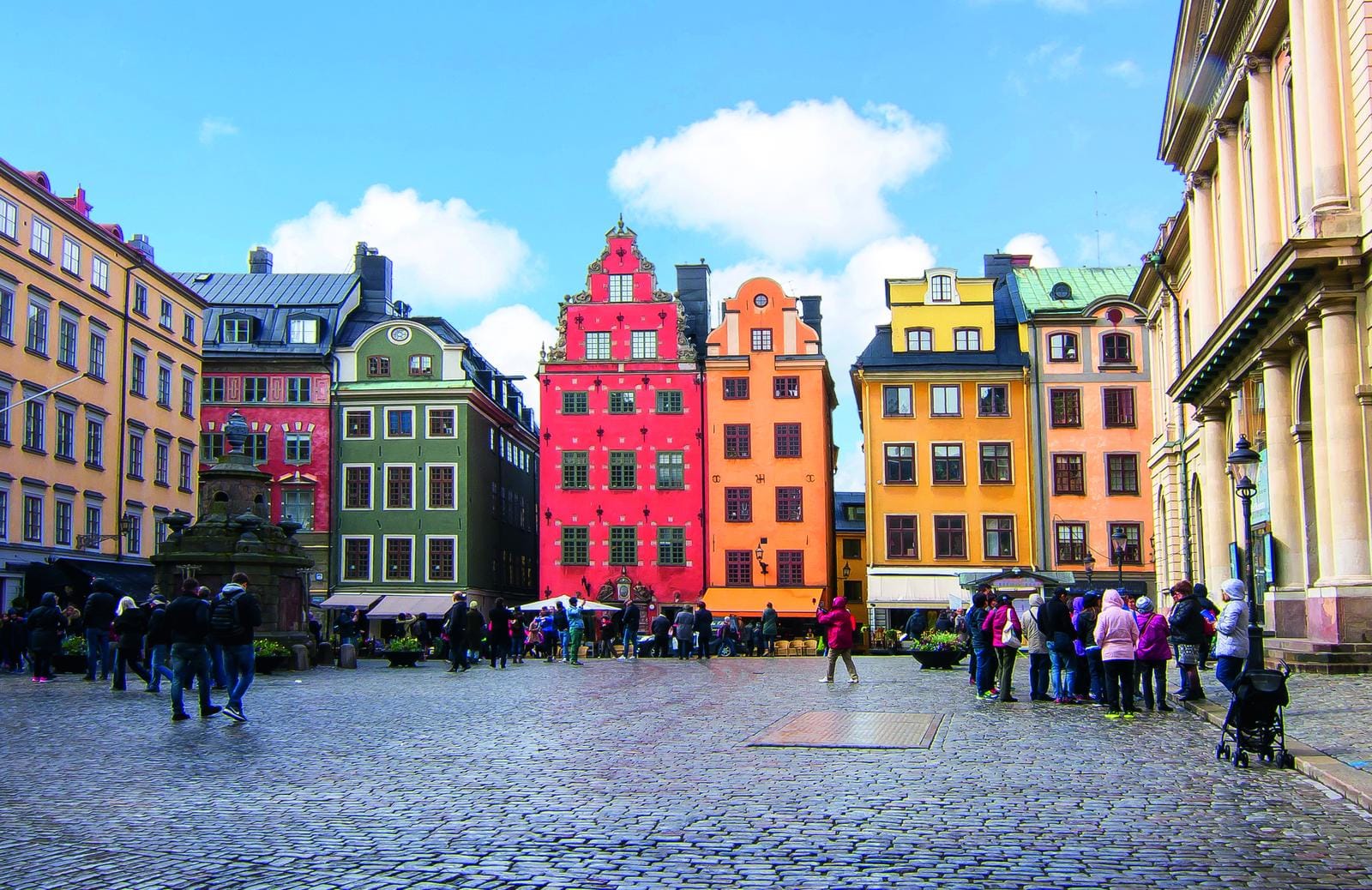 Bunte historische Gebäude und belebter Platz in Stockholm, Schweden, unter blauem Himmel.