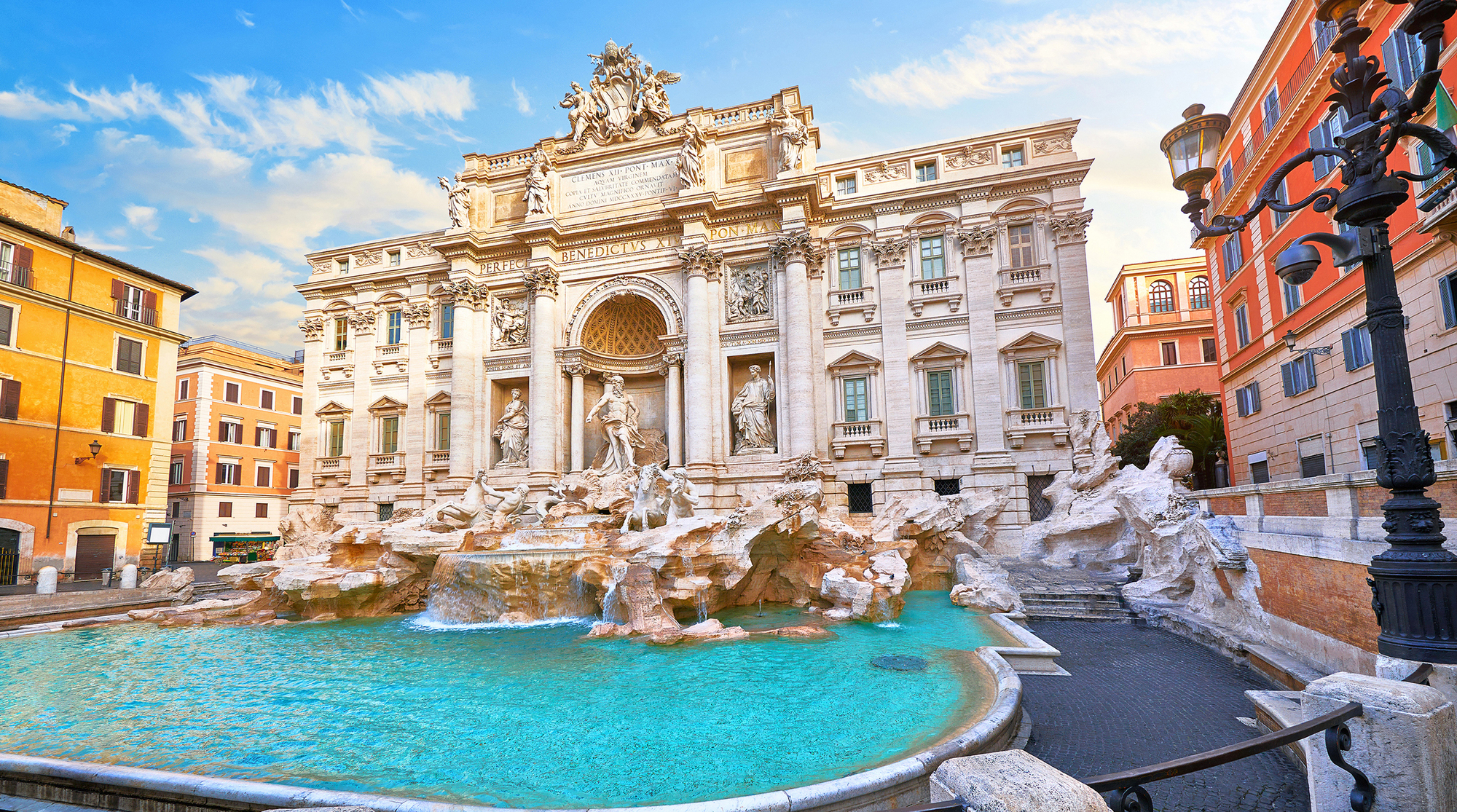 Trevi Fountain in Rome, Italy. Ancient fountain. Roman statues at piazza in old medieval city among traditional italian houses and street lamps. Famous landmark. Touristic destination for vacation.